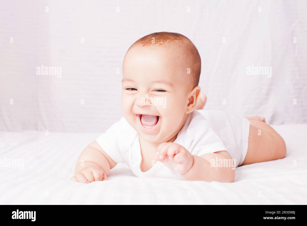 Adorable baby lying on the stomach at the white Stock Photo Alamy