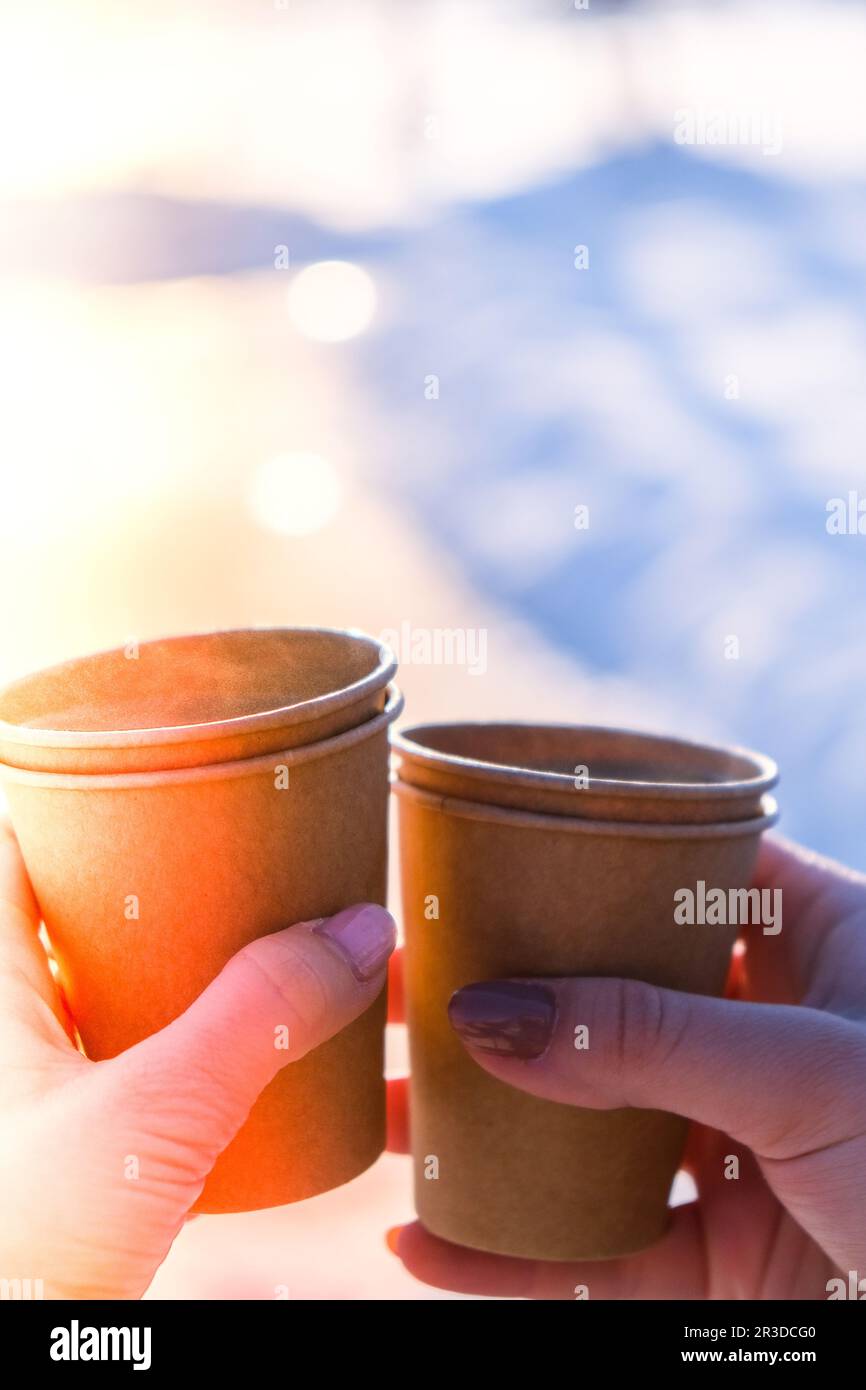 Womans hand with paper cup of coffee in winter snow background ...