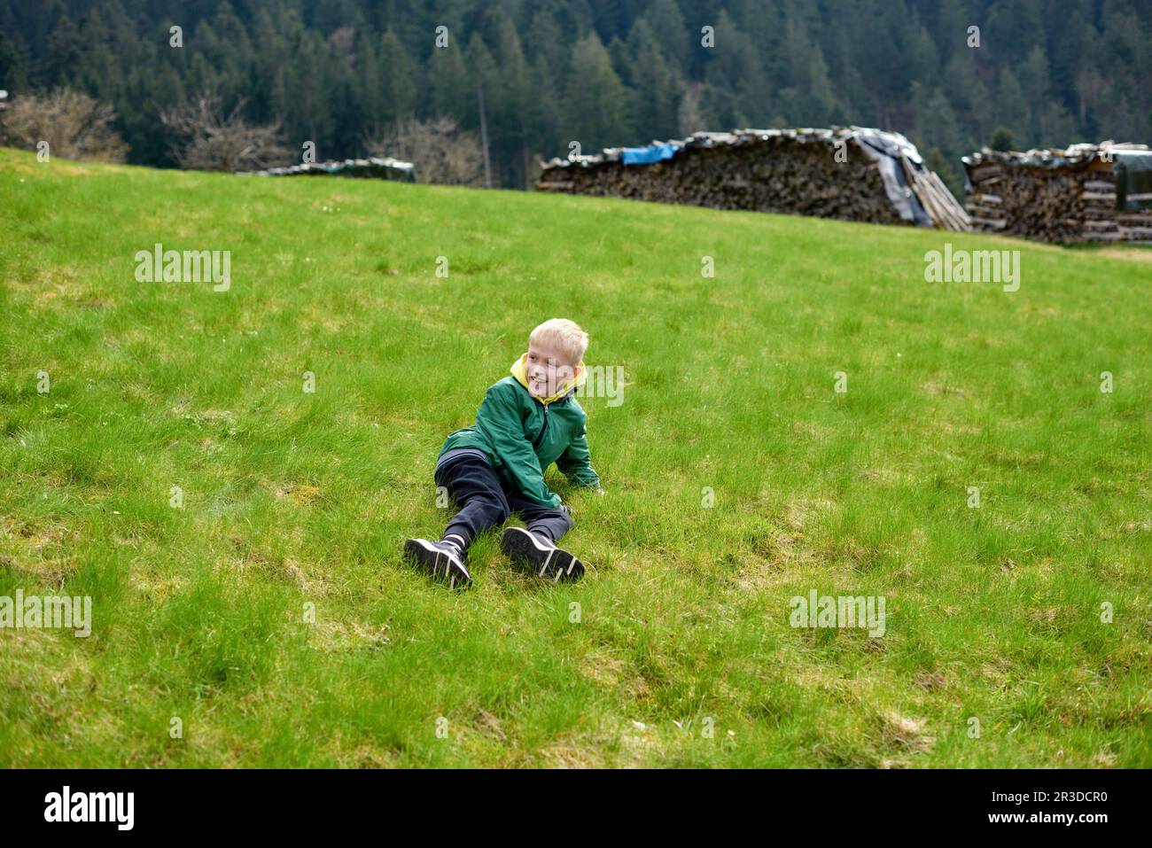 Fun teenager sits on hillside. Boy resting in mountains. School boy