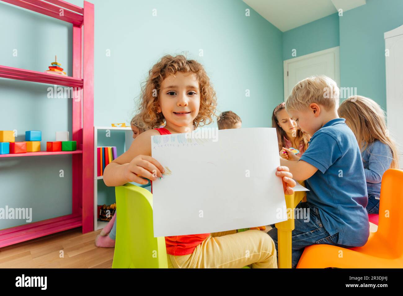 Happy little girl showing her drawing to the camera Stock Photo - Alamy
