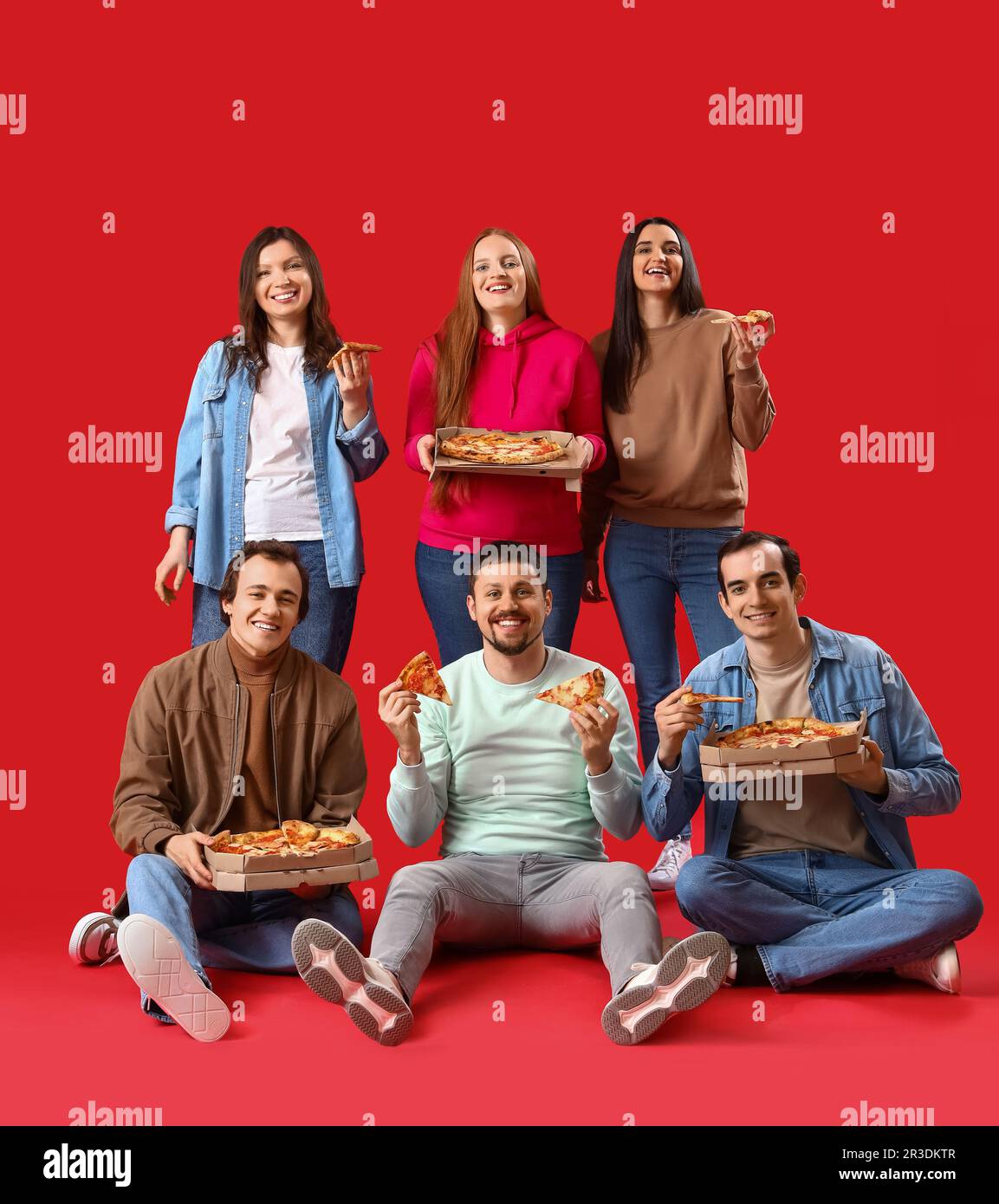 Group of friends with tasty pizza on red background Stock Photo - Alamy
