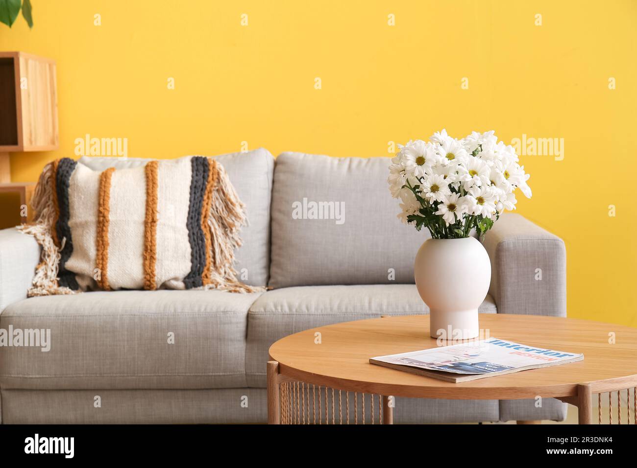 Vase with chrysanthemum flowers and magazine on wooden coffee table in living room Stock Photo