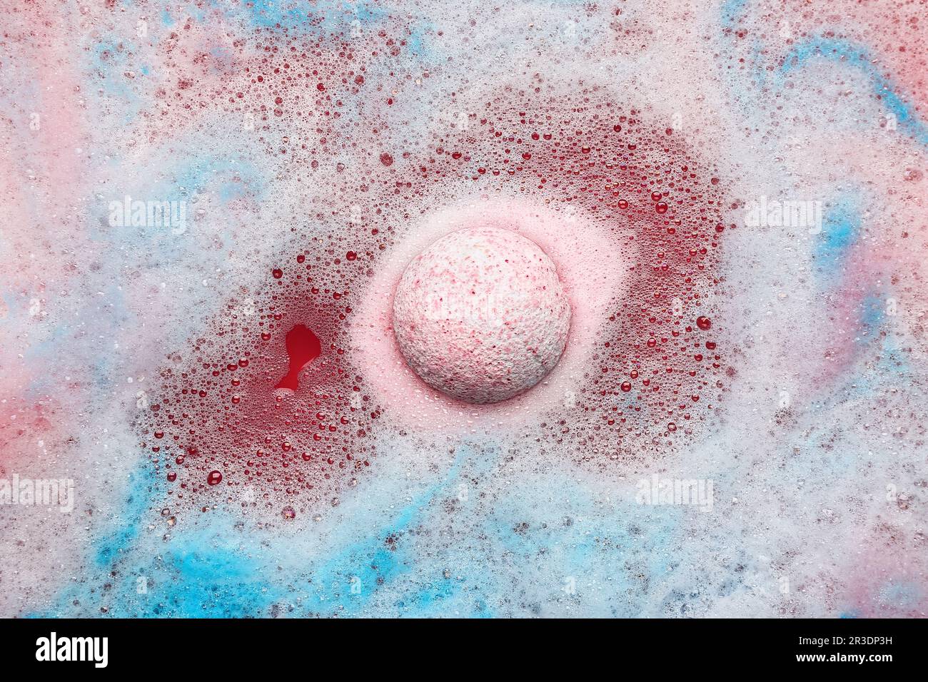 Pink bath bomb dissolving in blue water Stock Photo - Alamy