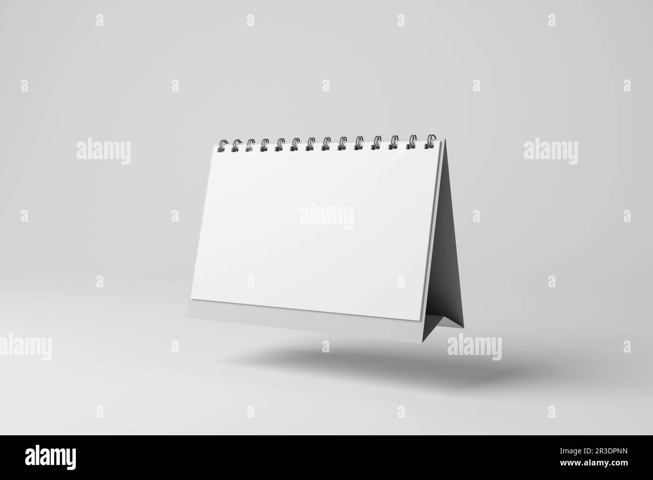White monthly desktop calendar floating in mid air casting shadow on white background in grayscale monochrome. Business schedules and appointments Stock Photo