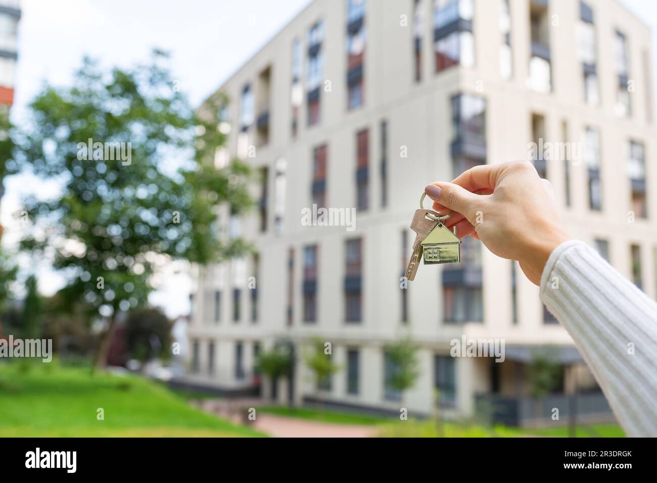 Hand holding keys on the background of a new building, construction
