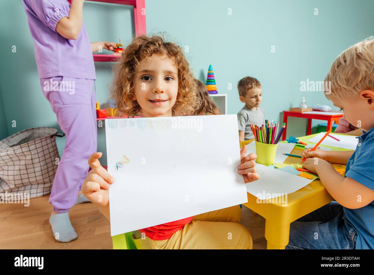 Happy little girl showing her drawing to the camera Stock Photo - Alamy
