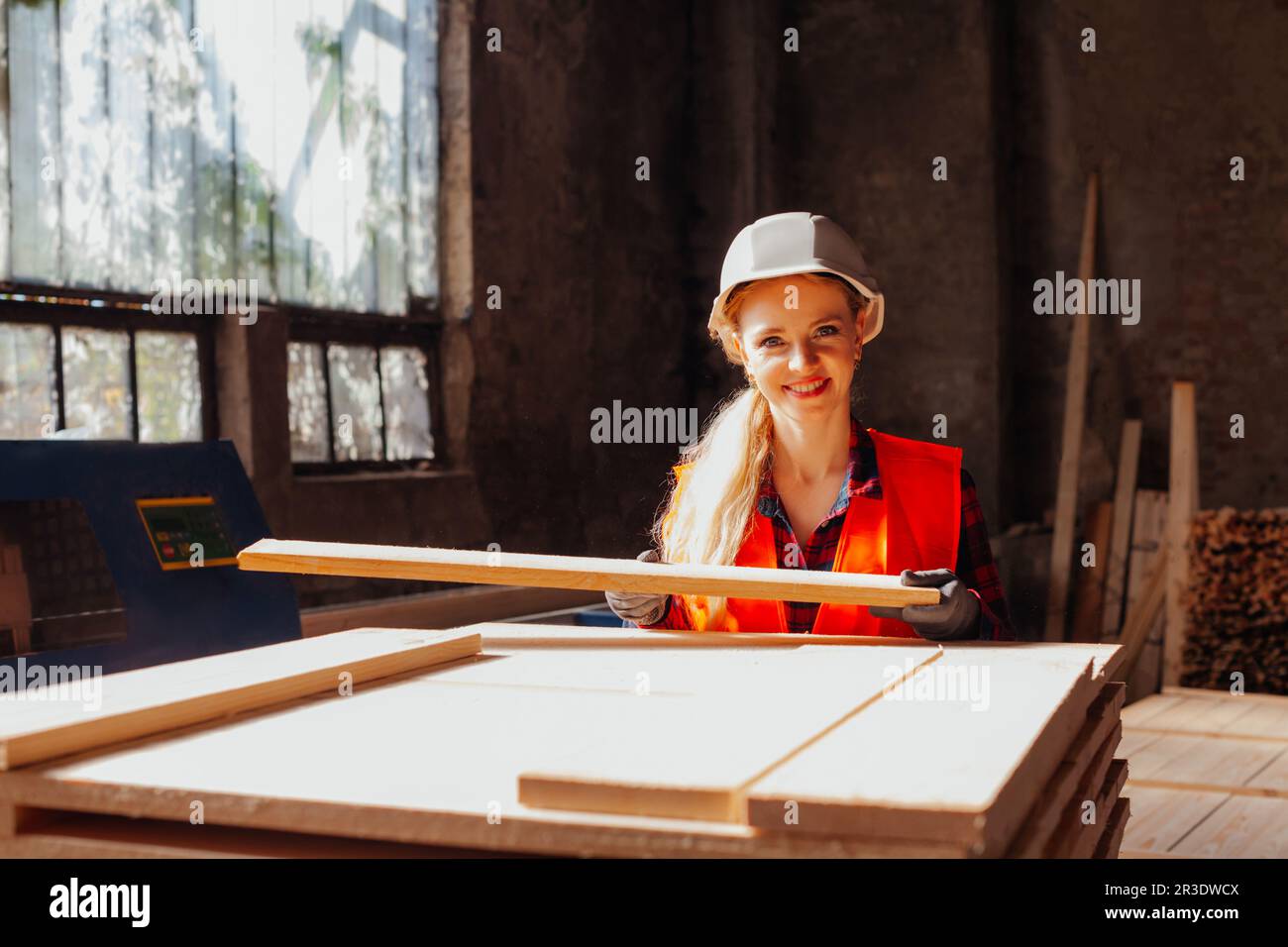 Attractive woman woodwork factory worker holding wooden plank Stock Photo