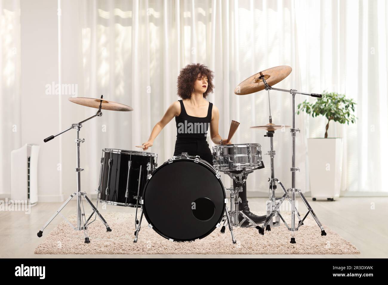Young female musician practicing drums at home Stock Photo