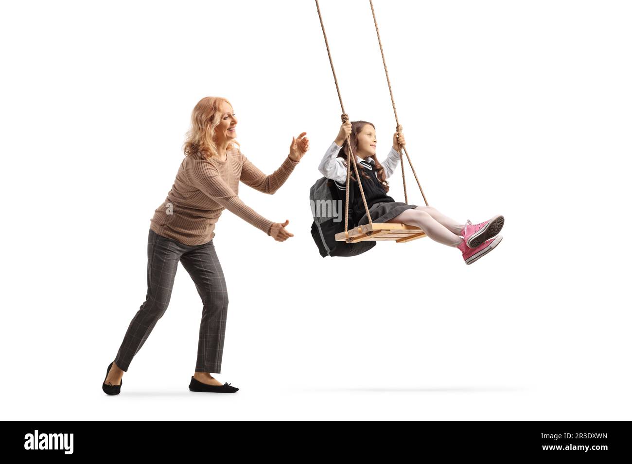 Woman pushing a schoolgirl on a swing isolated on white background Stock Photo