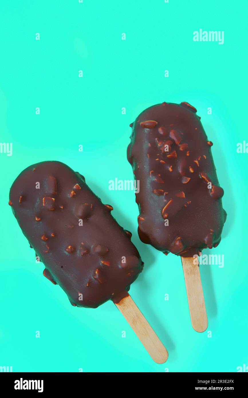 Cake - popsicle in Chocolate glaze on a blue background. space for text. Ice cream sweet eskimo with chocolate icing.  Chocolate Stock Photo