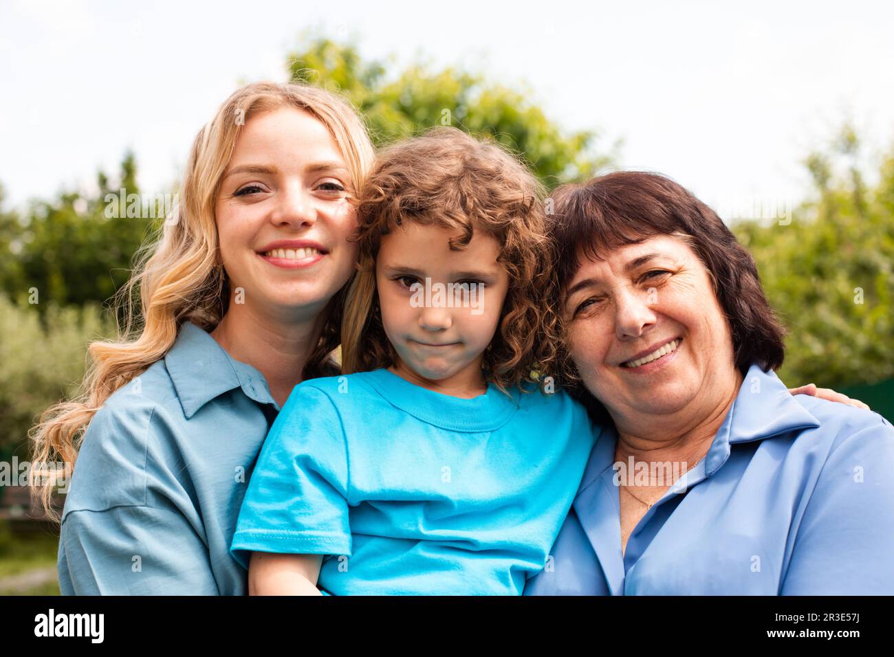 Cute girl embracing mother and grandmother outdoors Stock Photo