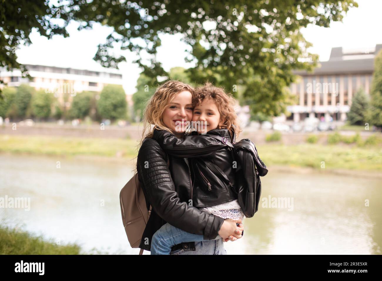 The daughter kisses her mom while walking in the waterfront Stock Photo