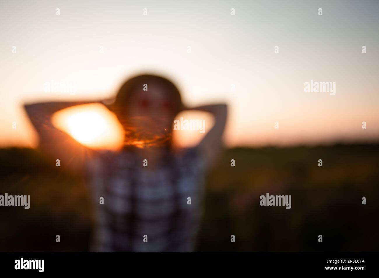 Blurred image of a young girl on sunset sky background Stock Photo