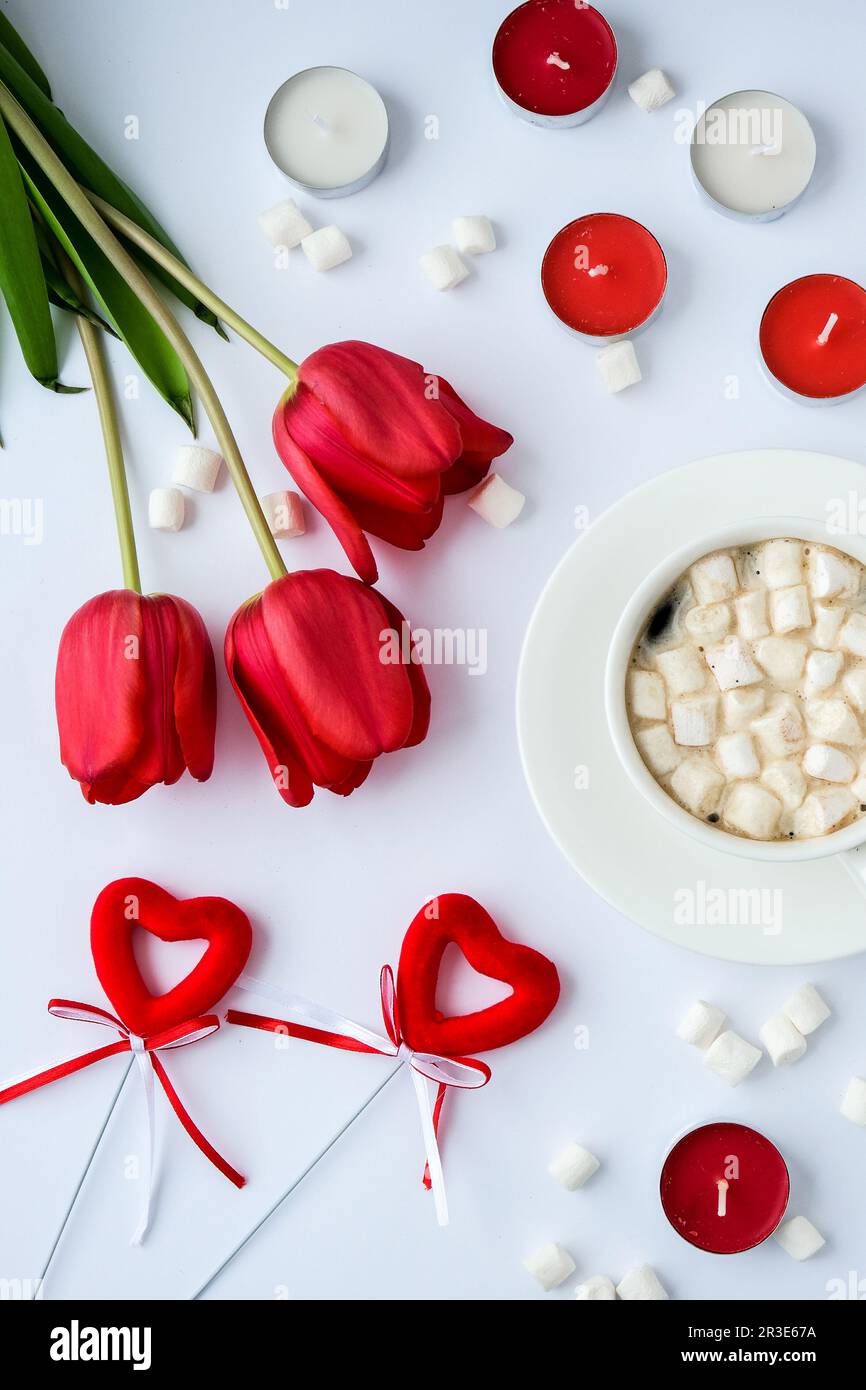 Copy space for text. Red tulips candles White cup of cacao marshmallows morning breakfast. Holiday background. Greeting card. Va Stock Photo
