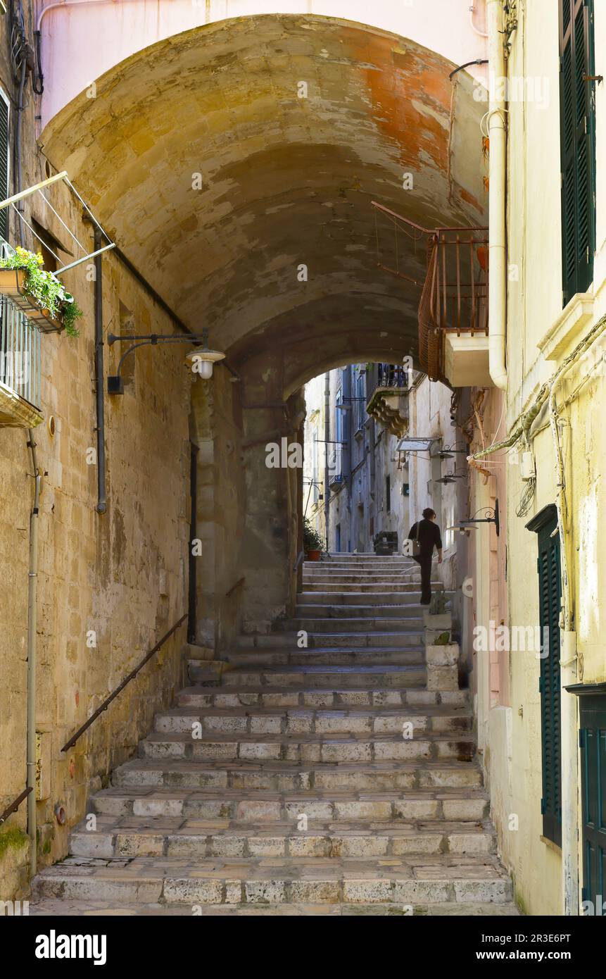 Moments in local daily life in the historic Sassi of Matera, Basilicata region of Italy. Solitary figure, ascending the stairs of old street. Stock Photo
