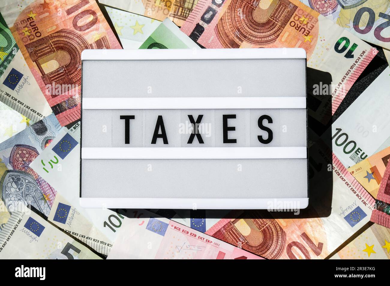 Lightbox board with word TAXES in black letters around Euro banknotes. Tax payment and filing concept. Money, Business, finance, Stock Photo