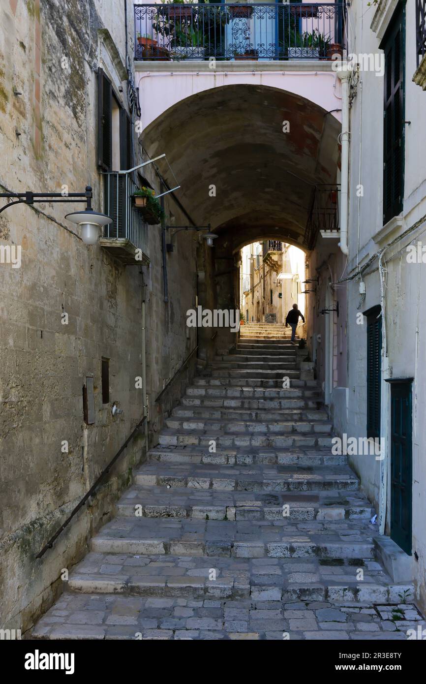 Moments in local daily life in the historic Sassi of Matera, Basilicata region of Italy. Solitary figure, ascending the stairs of old street Stock Photo