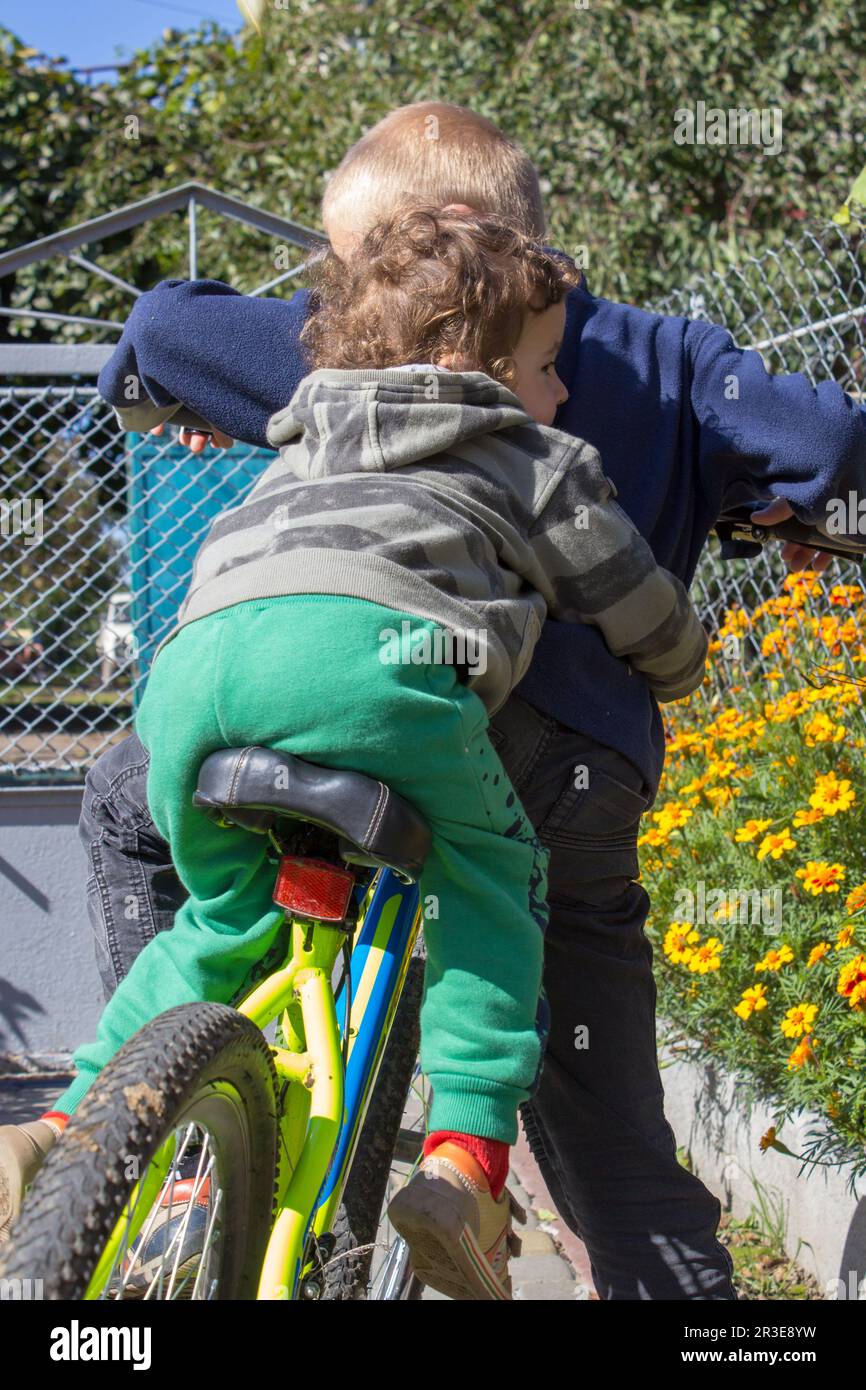 the two boys sit on the bike view the back Stock Photo - Alamy