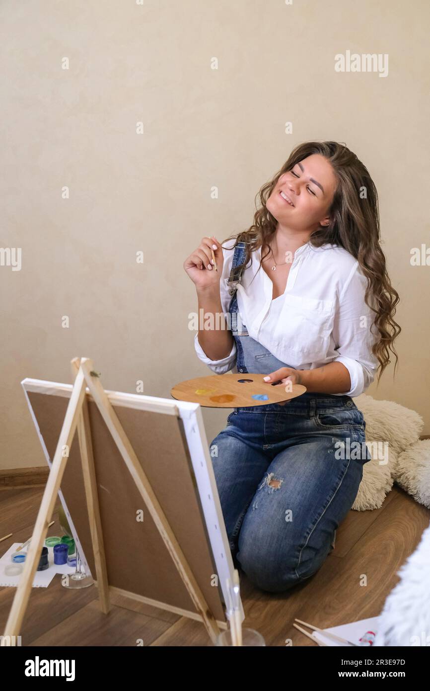 Creative painter in working process. Artist workplace, hobby, craft tools. Artist female canvas painting. Professional young wom Stock Photo