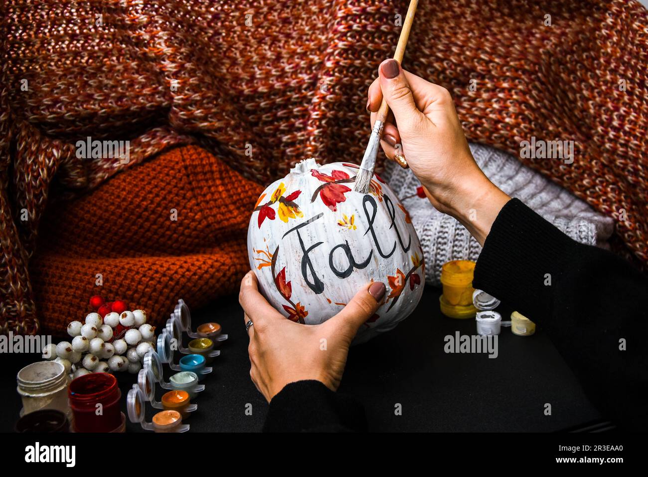 DIY. Do it yourself. Woman paints thanksgiving decorations on orange pumpkin for Halloween. Autumn harvest. Stock Photo