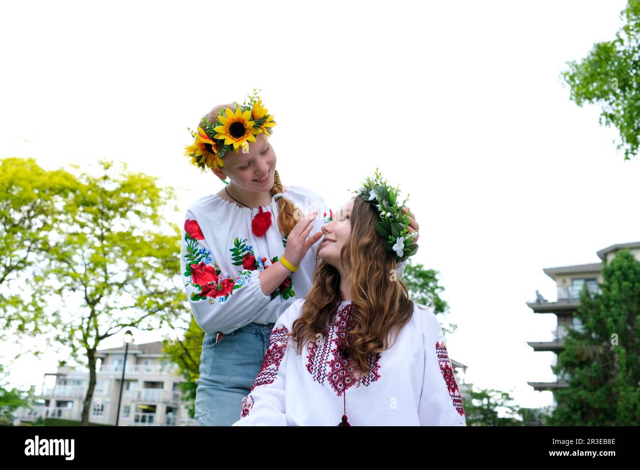 Two girls dress each other with a wreath of wildflowers. Weaving a ...