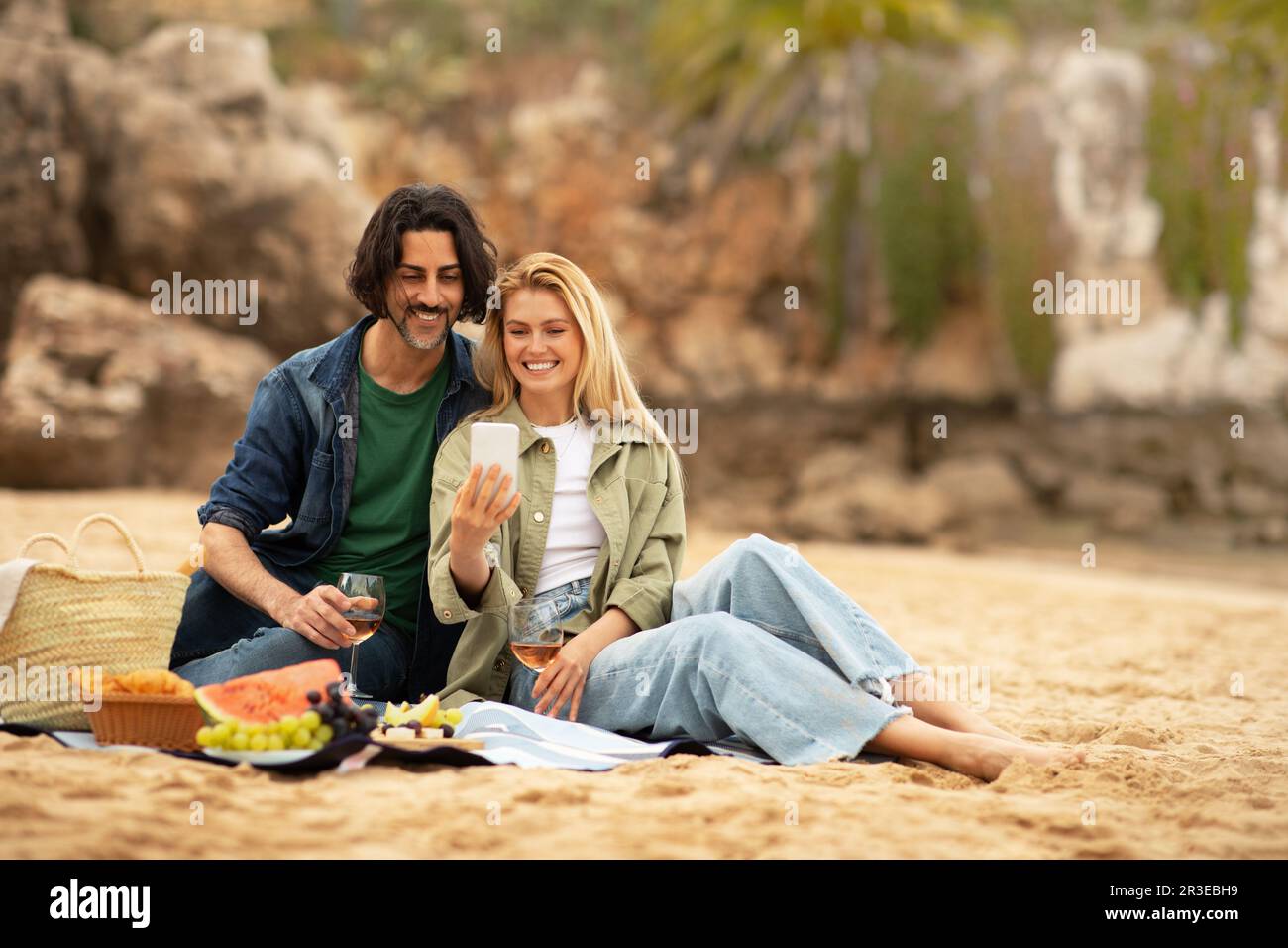 Romantic young couple taking selfie while having picnic at the beach Stock Photo