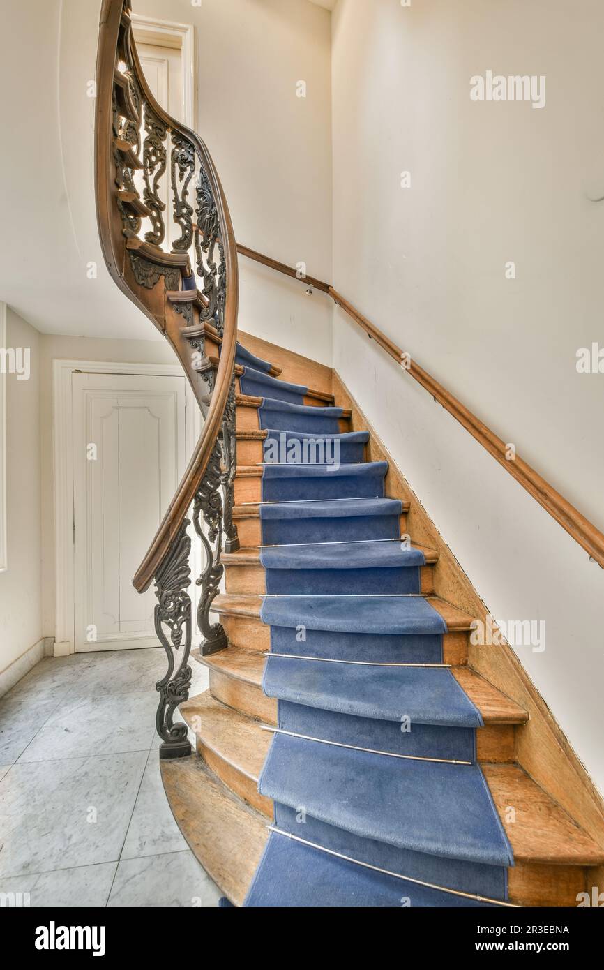 A Staircase With Blue Carpet On The Stairs And Wood Handrails In An Old 