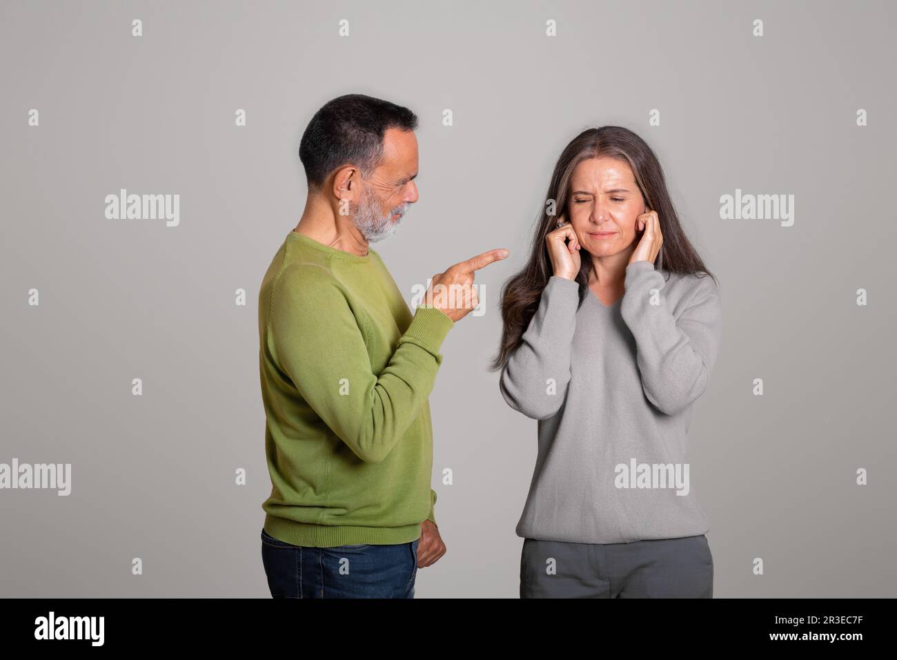Strict angry caucasian aged husband scolds his wife, lady covers ears