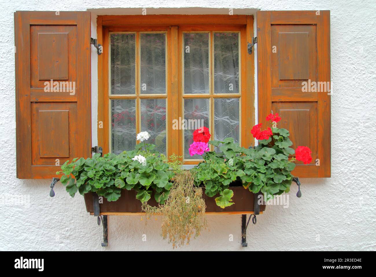 The picture was taken in the German countryside. The picture shows a traditional village house window. It opened the shutters and is decorated with fl Stock Photo