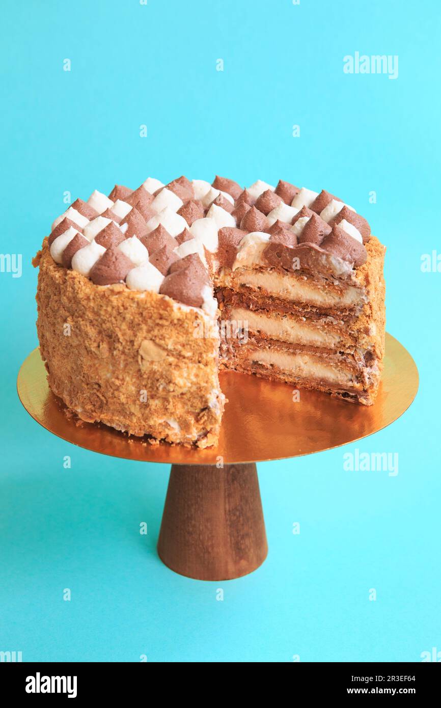 Sliced Birthday cake on the wooden cake stand. Beautiful sponge cake on the paper background. Copy s Stock Photo