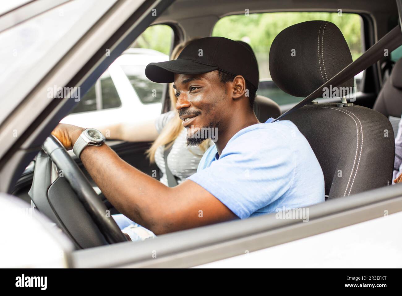 Cheerful young man driving car with friends on vacation Stock Photo