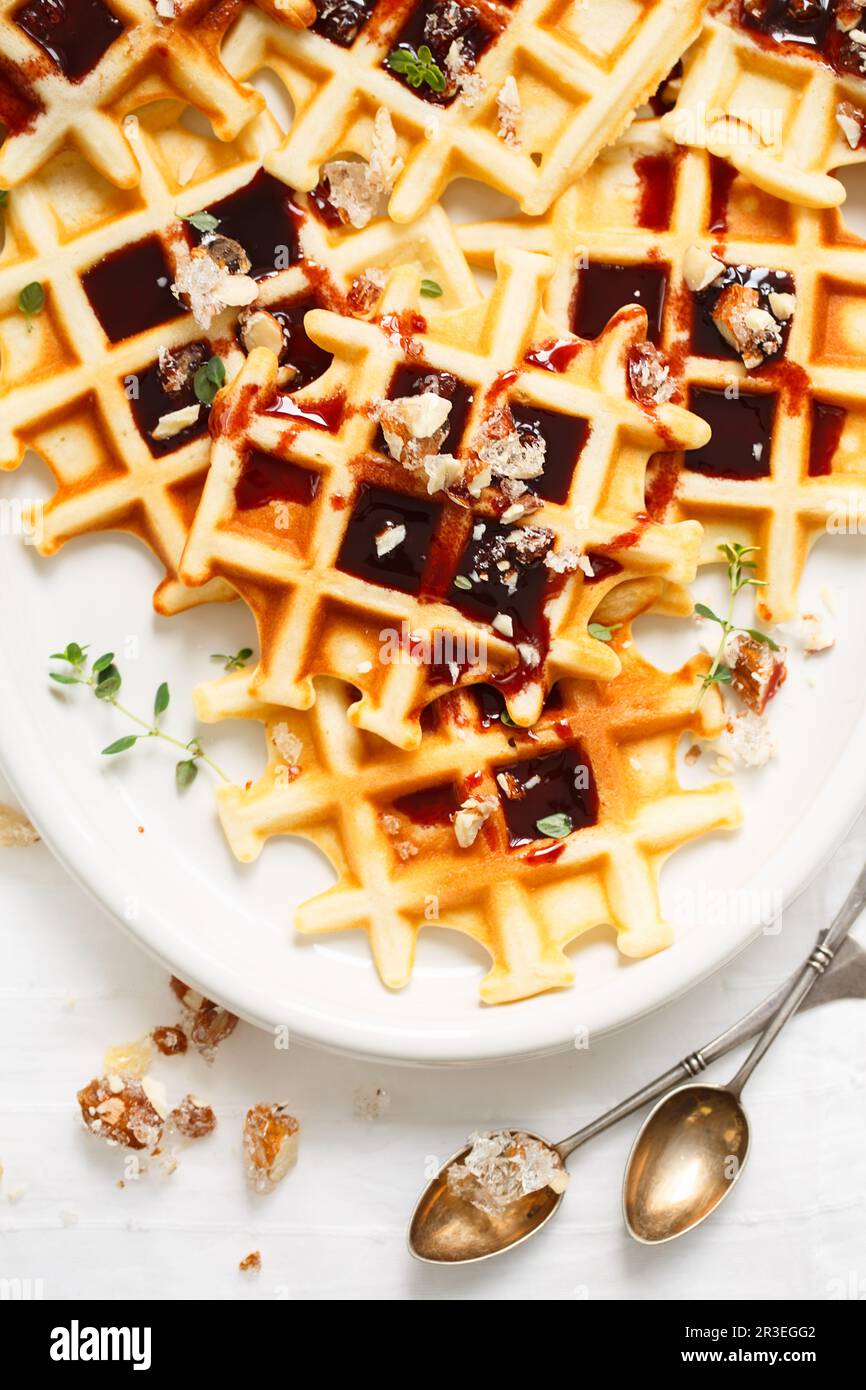 Belgian or Brussels waffles with date syrup or jam and candied roasted nuts. Homemade waffles in a w Stock Photo