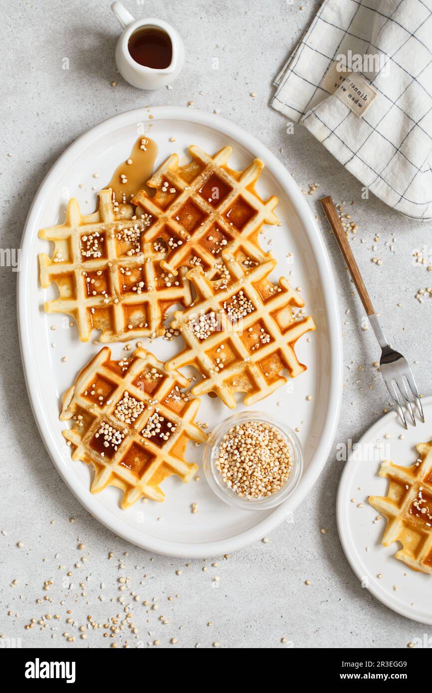 Belgian or Brussels waffles with maple syrup and puffed quinoa pops. Homemade waffles in a white ova Stock Photo