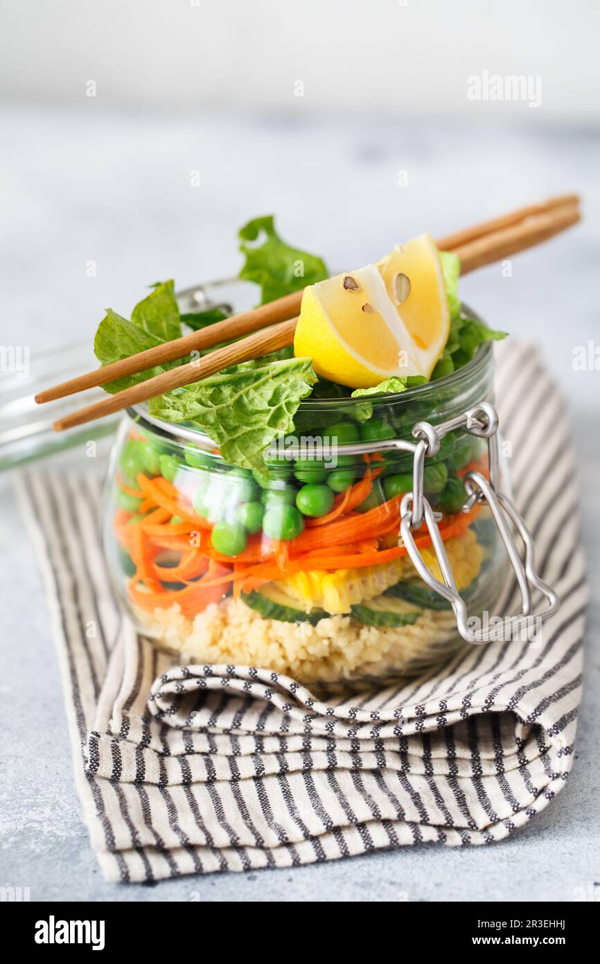 Glass jar with fresh raw vegetables and couscous groats. Healthy Meal Prep - recipe preparation photos. Healthy vegan dishes in Stock Photo