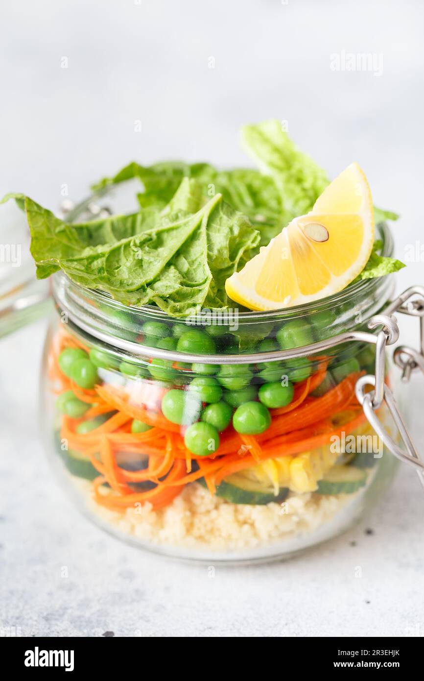 Glass jar with fresh raw vegetables and couscous groats. Healthy Meal Prep - recipe preparation photos. Healthy vegan dishes in Stock Photo