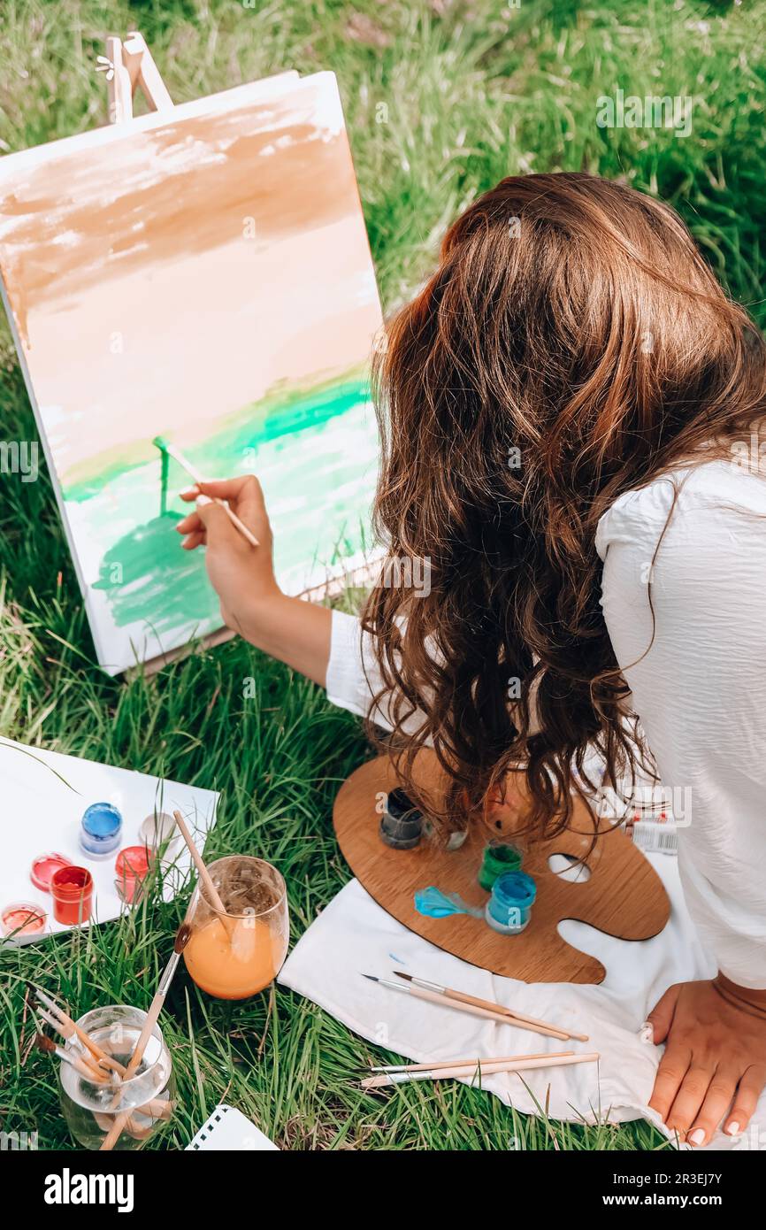 Artist painting on the easel outdoors in the garden. Open air outdoor ...