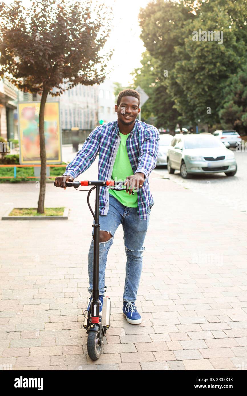 The young man with a scooter is posing in the city Stock Photo