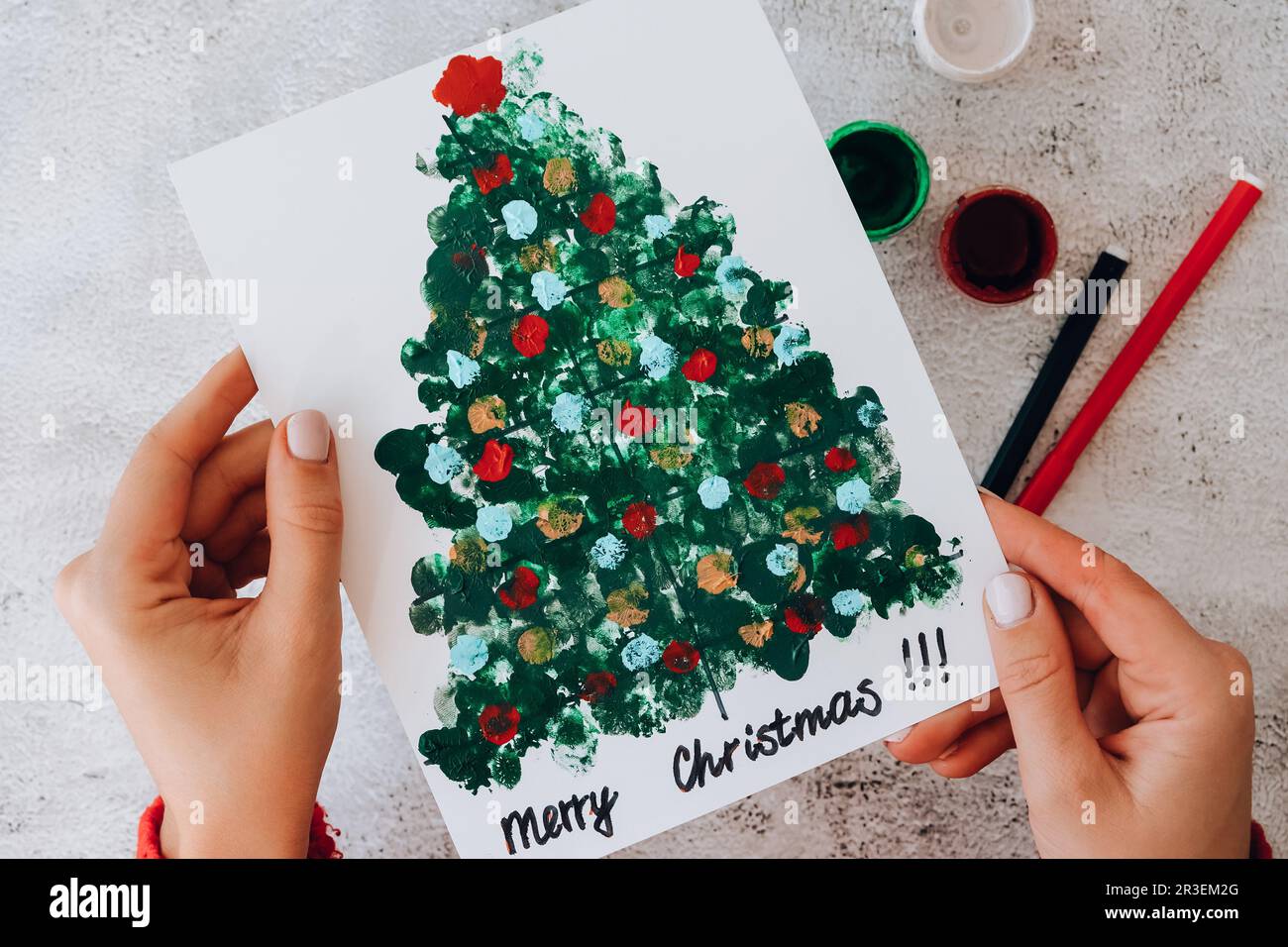 DIY Making greeting card Handmade crafts on holiday for children. Paint with fingers Merry Christmas tree. Step by step. Happy N Stock Photo