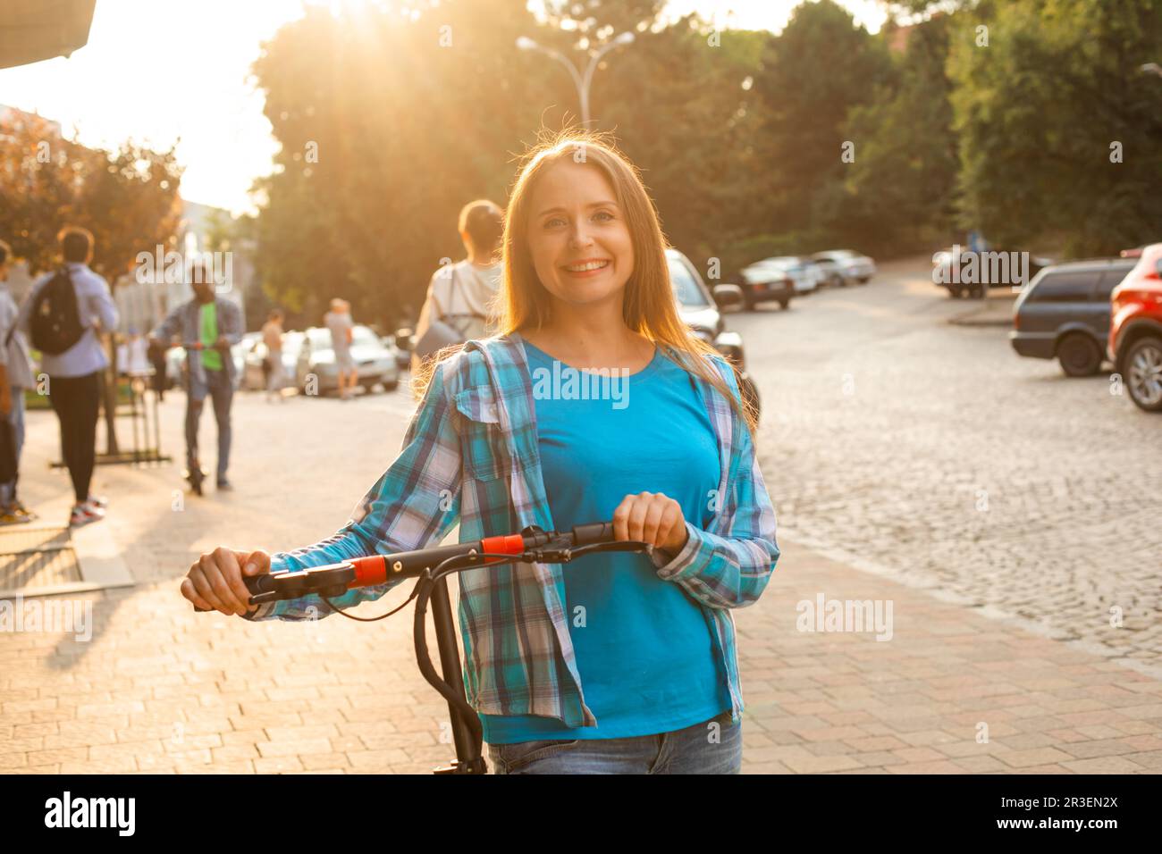 The beautiful woman enjoys riding an electric scooter Stock Photo