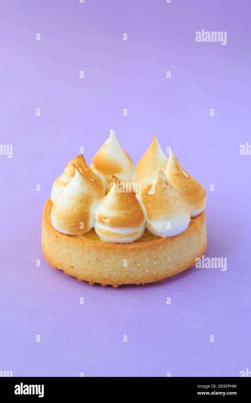 Tartlet with lemon curd over the violet background. close-up of Lemon meringue mini pie with browned meringue Stock Photo