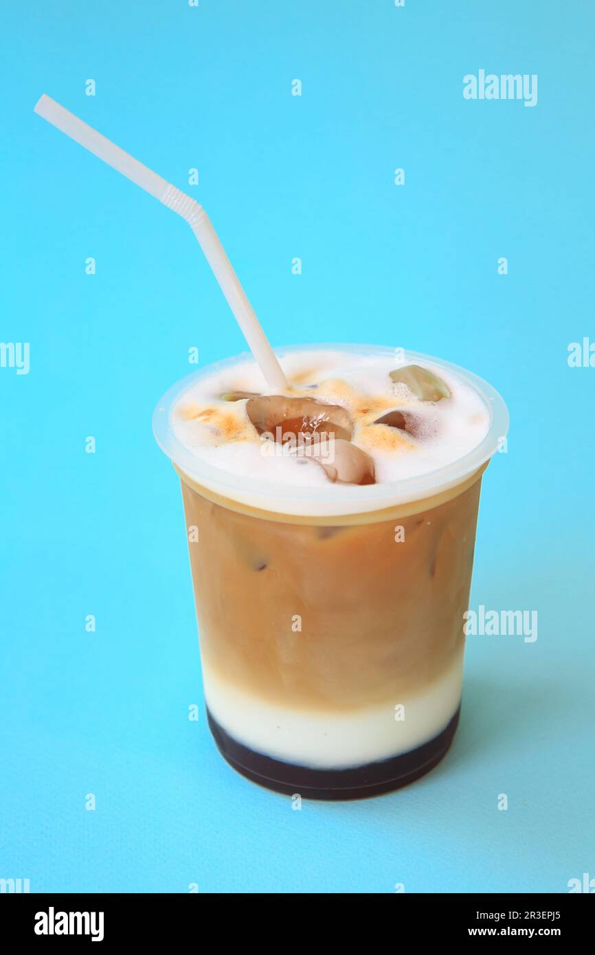 A glass with ice latte coffee cocktail, cold refreshing drink or beverage with ice on blue Stock Photo