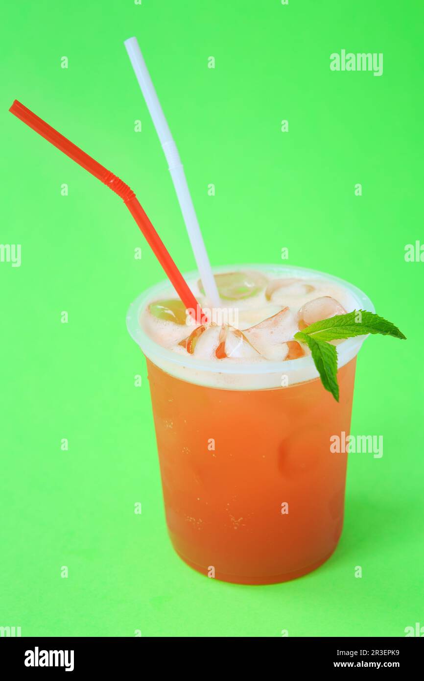 A glass with red lemonade with mint, cold refreshing drink or beverage with ice on green Stock Photo
