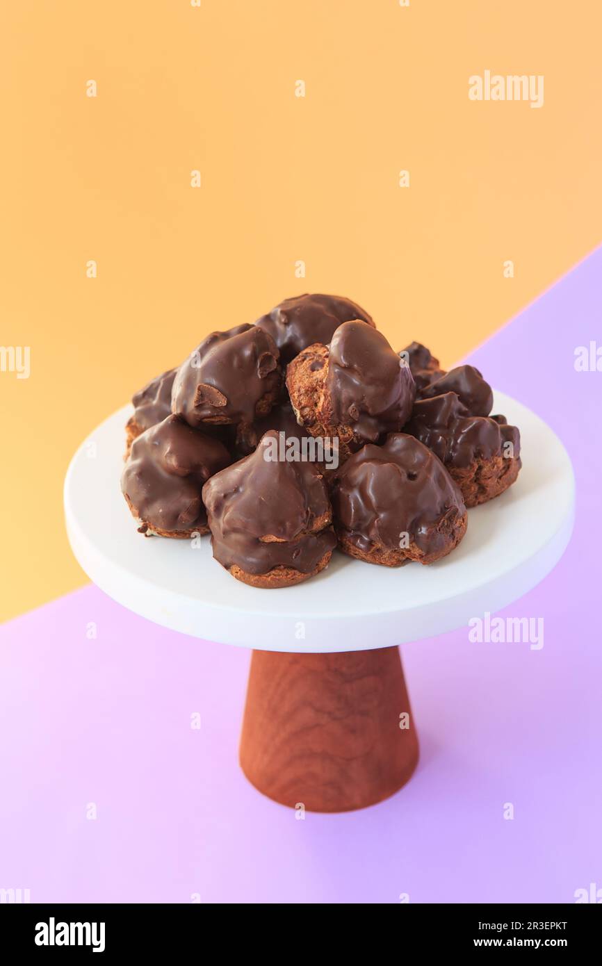 Homemade profiteroles with chocolate. Cream puffs filled chocolate vanilla custard on a bright background. Profiteroles with cre Stock Photo