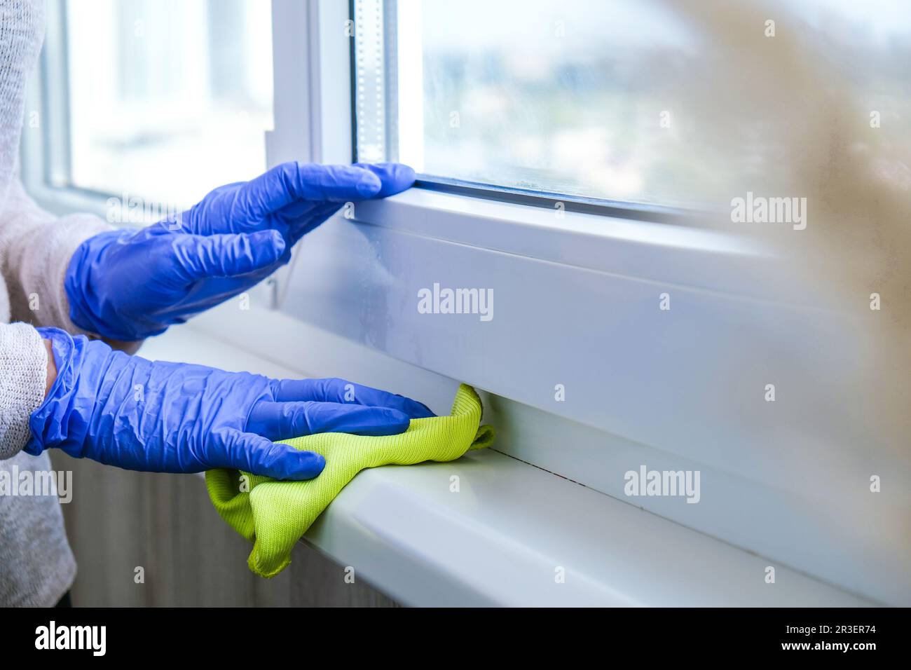 Cleaning the windowsill wiping dust by blue microfiber cloth for