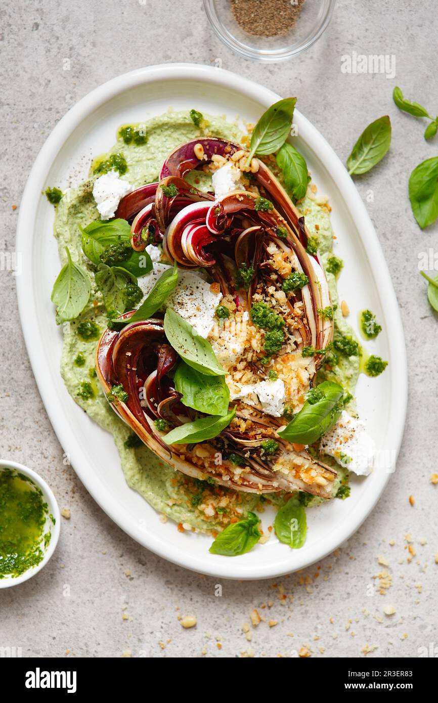 Roasted radicchio salad with feta, green tahini, Pine nuts and basil pesto. Radicchio rosso di trevi Stock Photo