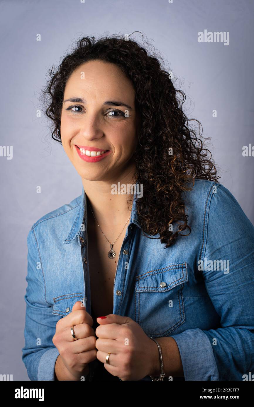 Young woman with curly black hair wearing blue denim shirt and hands grasping shirt Stock Photo