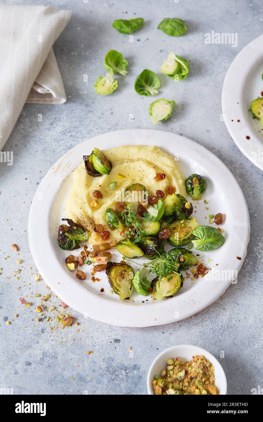 Brussels sprouts with pistachios, raisins and Skordalia (mashed potatoes). Healthy Meal preparation. Plant-based dishes. Green l Stock Photo