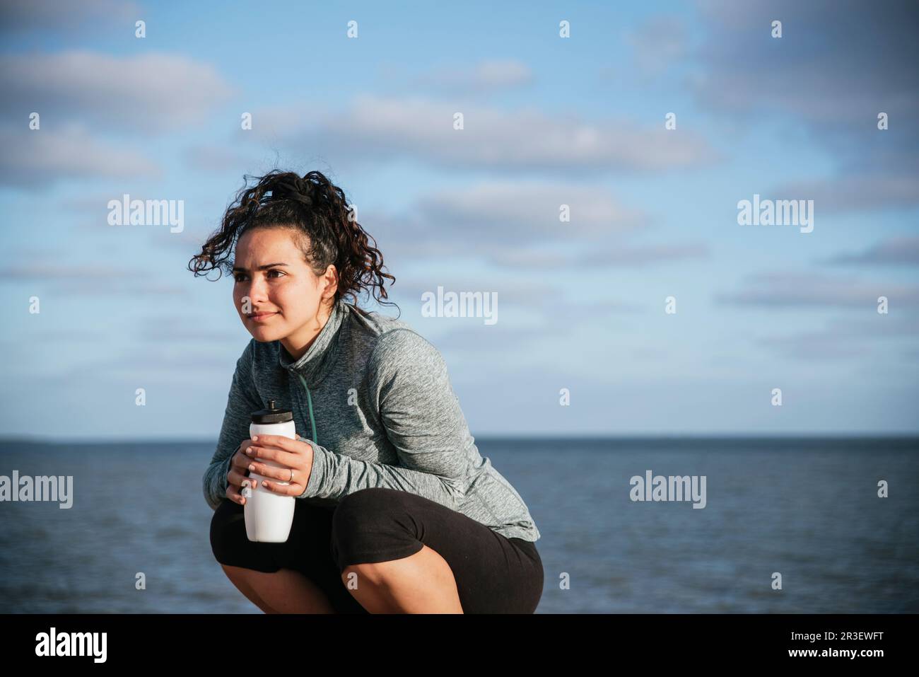 runner girl squatting drinking water Stock Photo Alamy