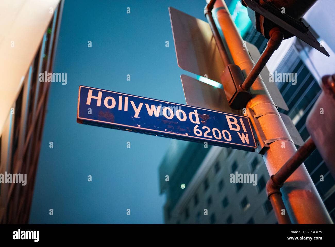 Upward looking angle of a Hollywood Boulevard street sign is illumniated by the lights of the City of Los Angeles during a cloudy night. Stock Photo