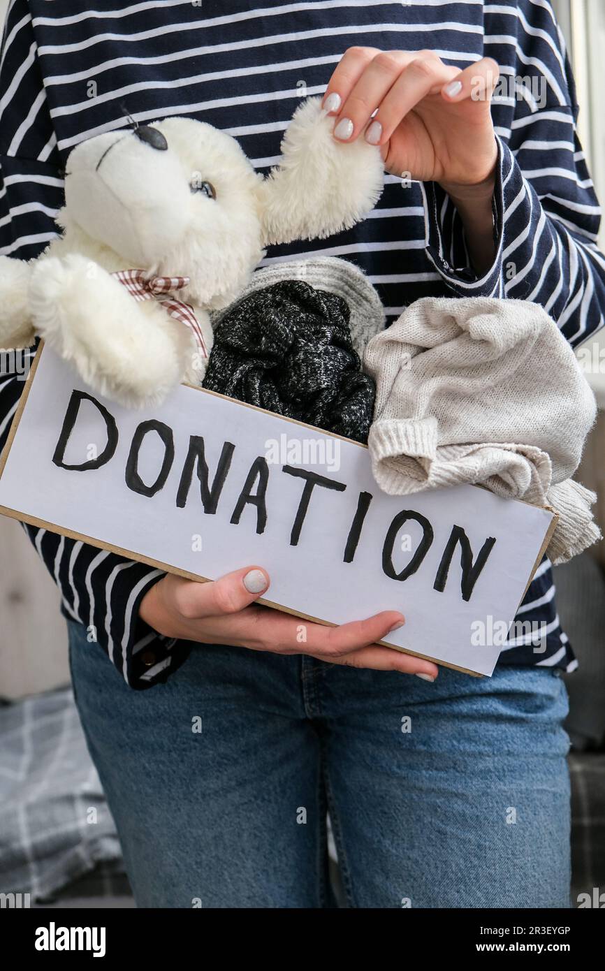 Female volunteer holding donation box with old used toys and clothes